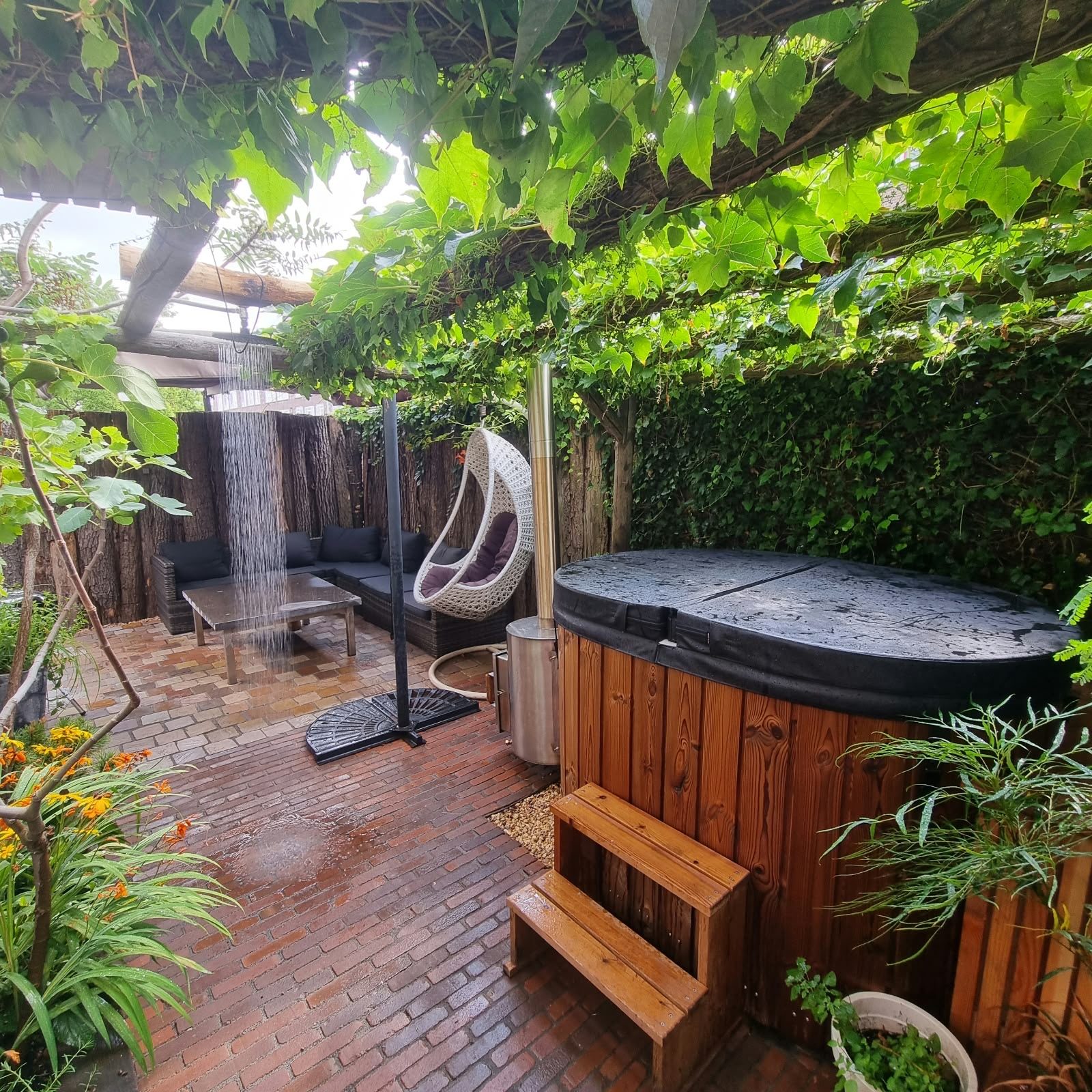 Tuin met houten hottub onder een pergola met druivenranken