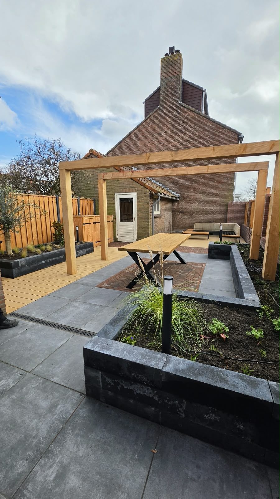 Tuin met pergola en zwarte plantenbakken