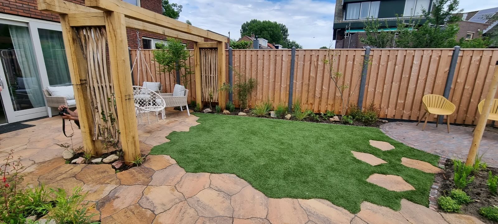 Tuin met houten pergola, kunstgras en stapstenen