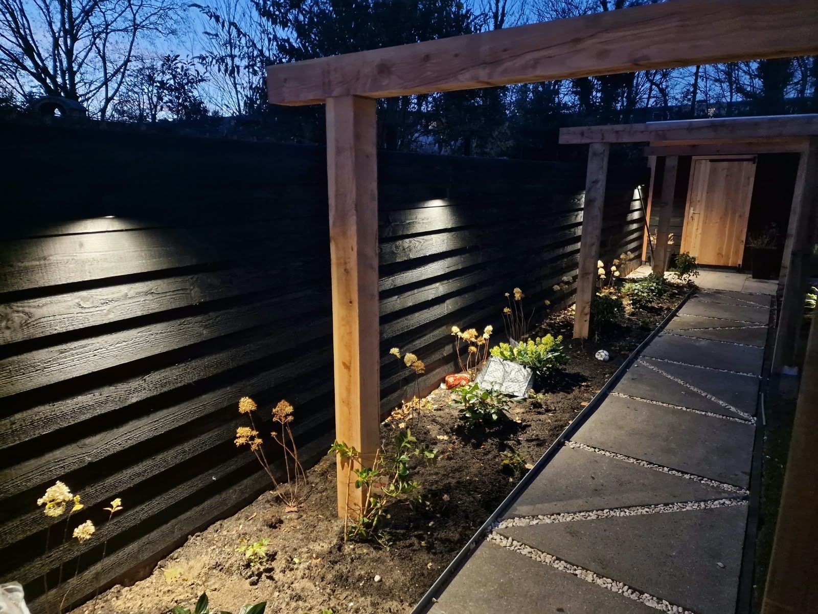 Verlichte schutting en tuinpad in de avond